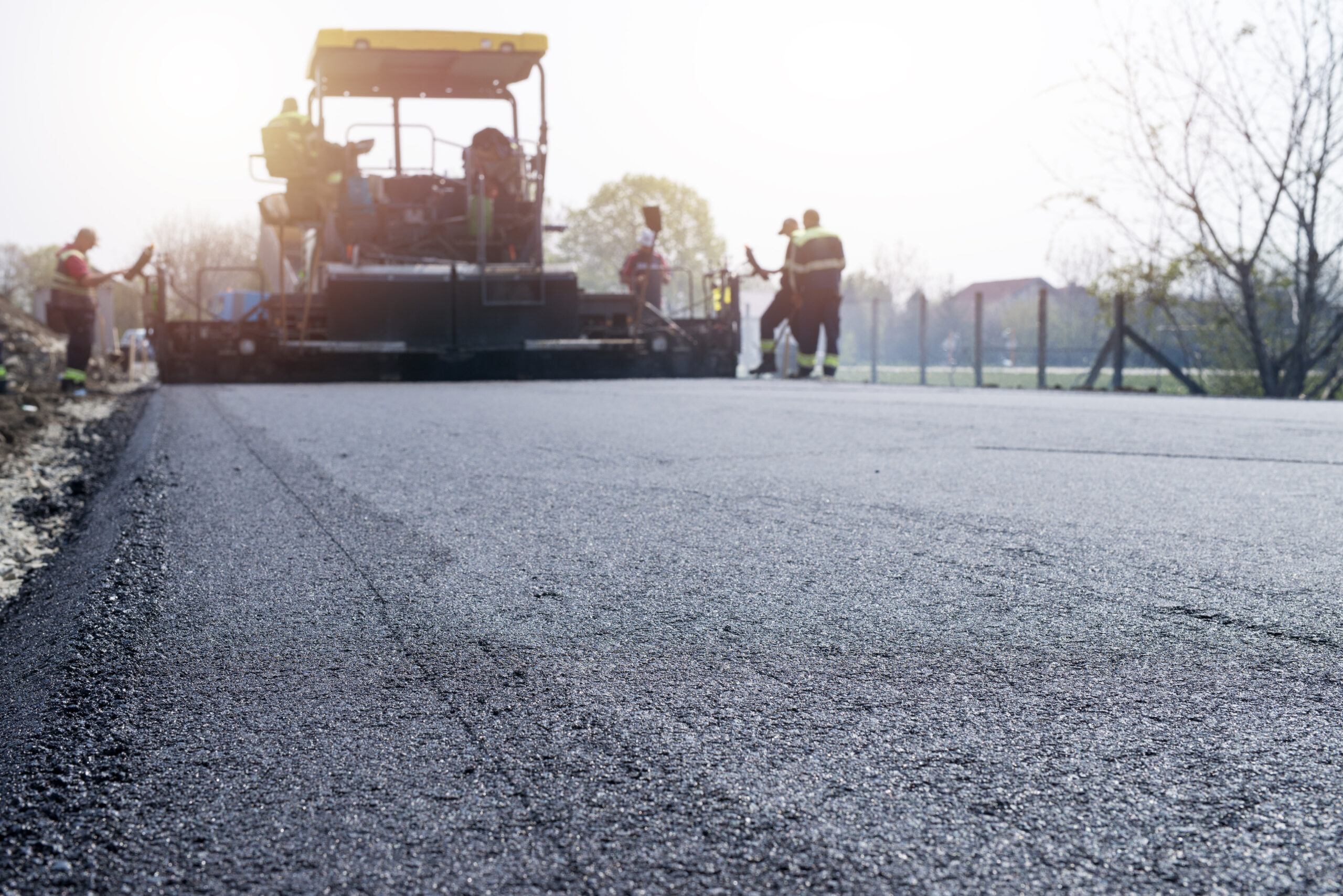 Workers placing new coating of asphalt on the road. Workers placing new coating of asphalt on the road.